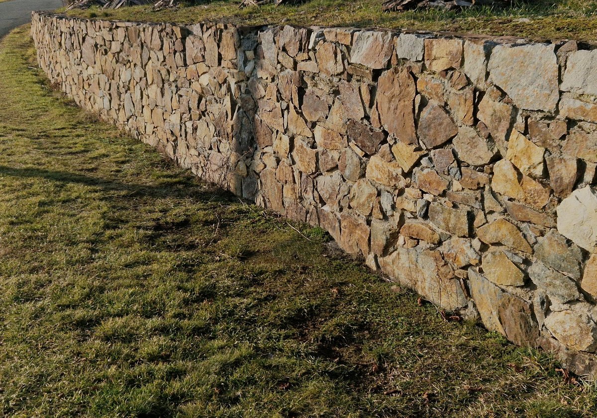 Stone wall being reconstructed by stonemason in a park