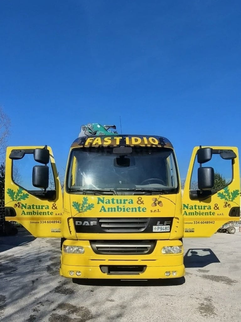 Tre camion gialli Natura & Ambiente parcheggiati in fila sotto un cielo blu