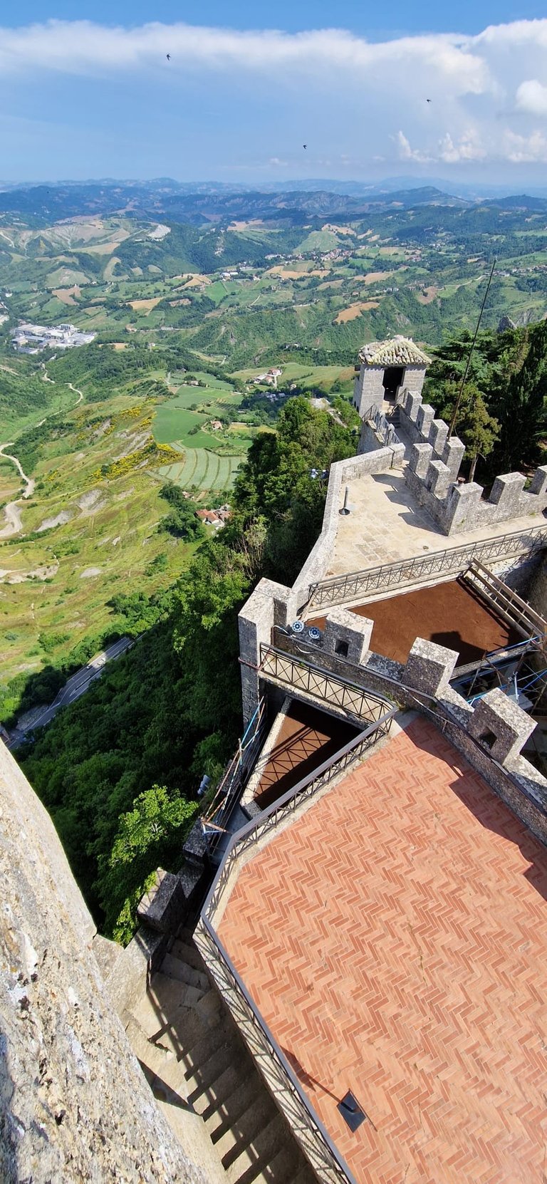 Aerial view from a hilltop fortress showing terraced green valleys and countryside landscape below